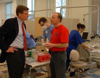 Senator Warner talks to a volunteer dentist at the Mission of Mercy Dental Clinic at NVCC's Fairfax Campus